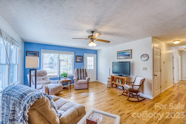 living room with a textured ceiling, ceiling fan, and light hardwood / wood-style flooring