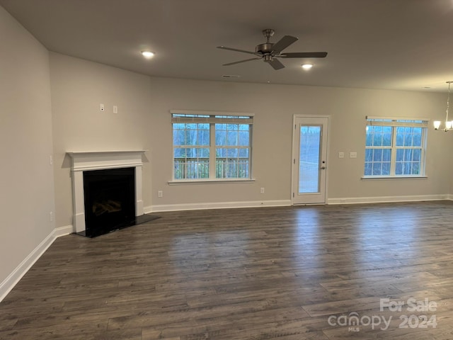 unfurnished living room with dark wood-type flooring and ceiling fan with notable chandelier