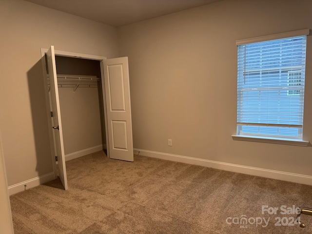 unfurnished bedroom with light carpet, a closet, and multiple windows