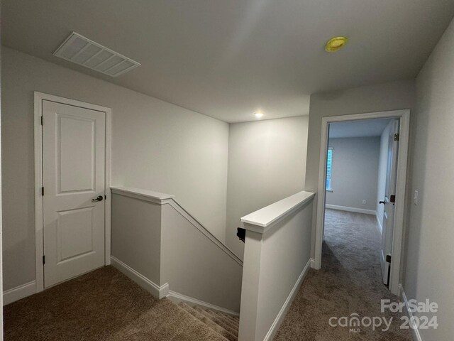 hall with dark colored carpet