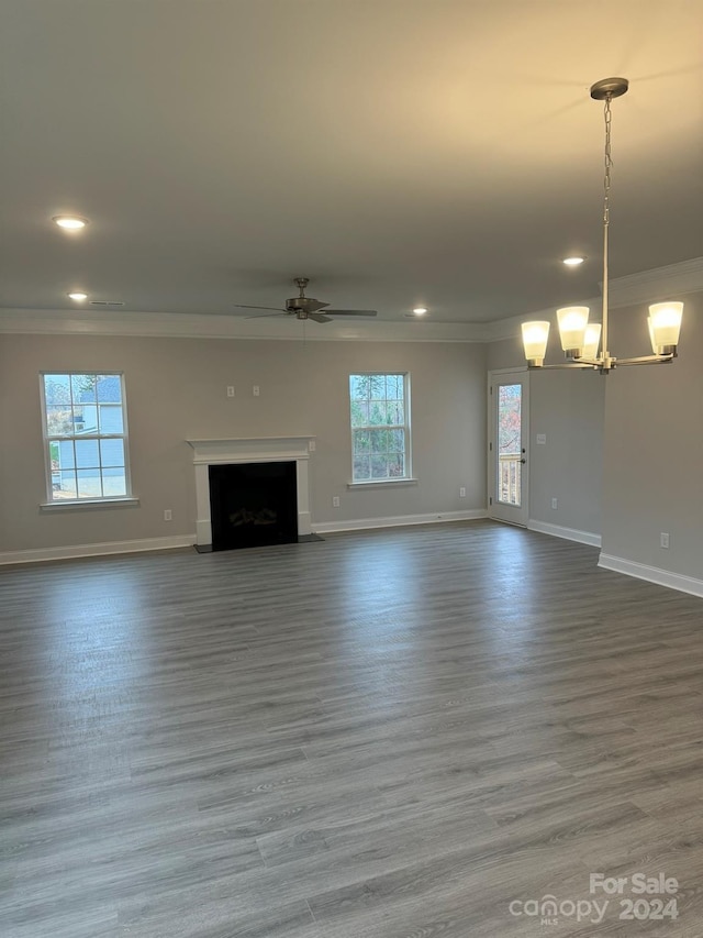 unfurnished living room featuring hardwood / wood-style floors, plenty of natural light, ornamental molding, and ceiling fan with notable chandelier