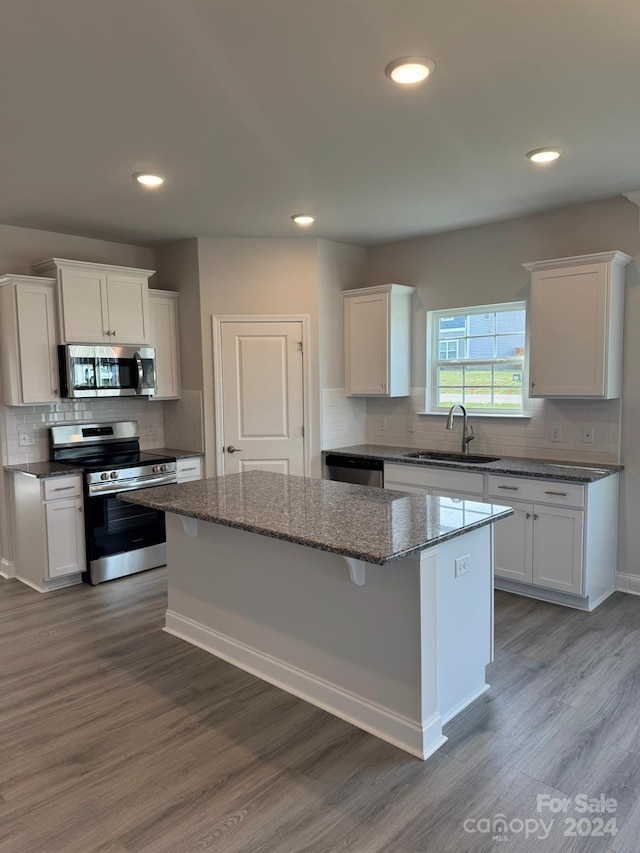 kitchen with white cabinets, a kitchen island, sink, and appliances with stainless steel finishes