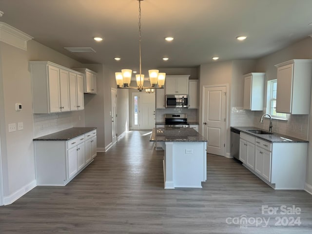 kitchen with white cabinets, sink, decorative light fixtures, a kitchen island, and stainless steel appliances