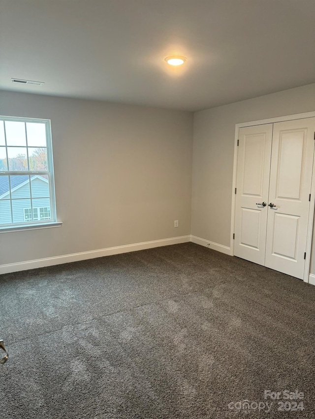 unfurnished room featuring dark colored carpet