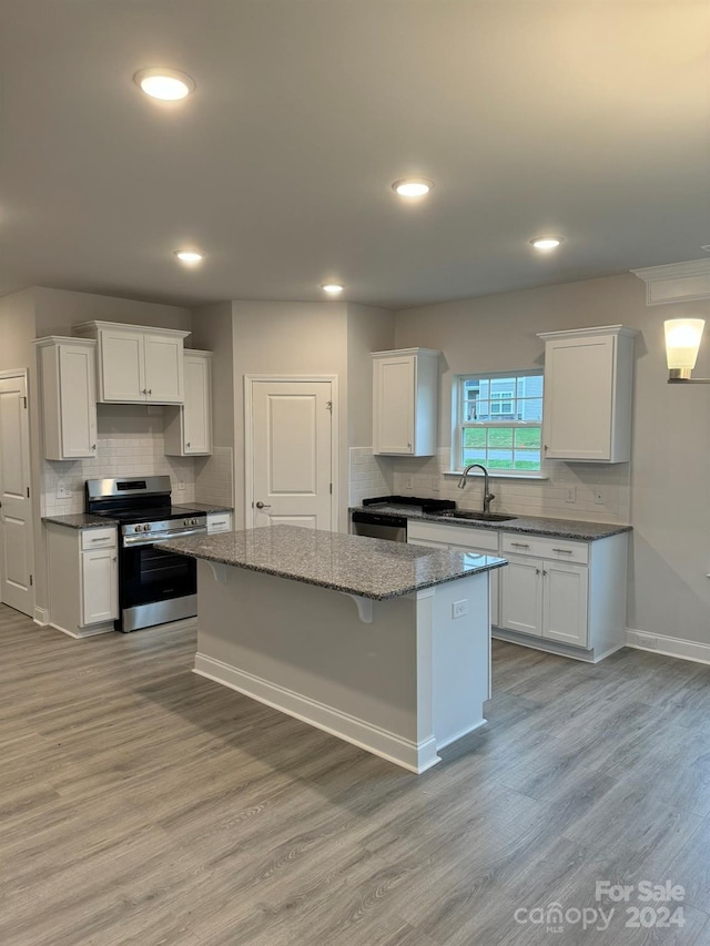 kitchen with a kitchen island, stainless steel range oven, and white cabinetry