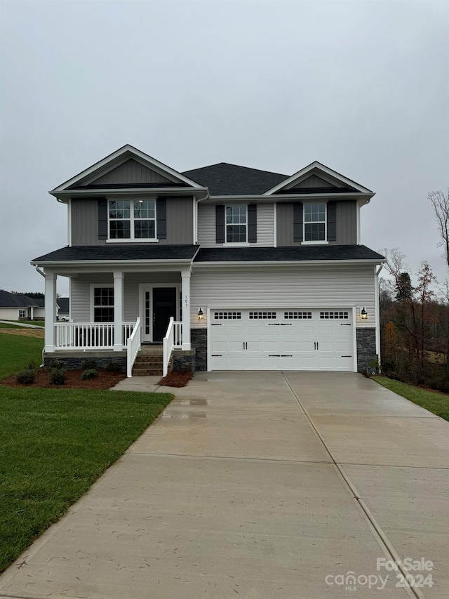 view of front of home with a front lawn, covered porch, and a garage