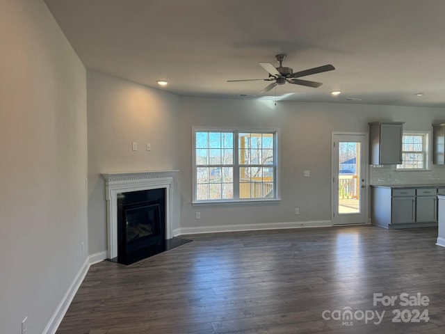 unfurnished living room featuring ceiling fan and dark wood-type flooring