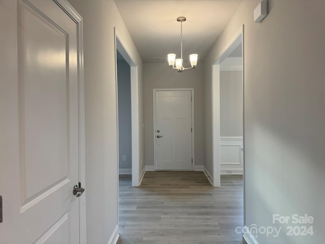 corridor featuring light hardwood / wood-style flooring and a chandelier