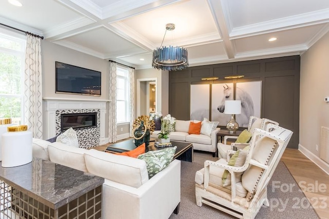 living room featuring crown molding, coffered ceiling, wood-type flooring, and a notable chandelier