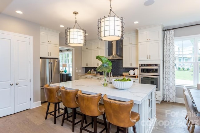 kitchen featuring appliances with stainless steel finishes, light hardwood / wood-style flooring, a center island with sink, a wealth of natural light, and tasteful backsplash