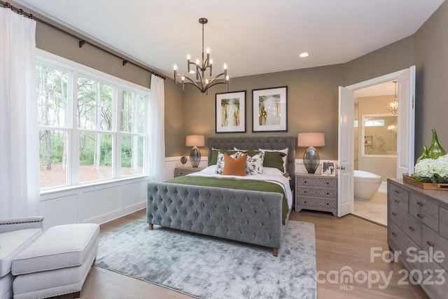 bedroom with a notable chandelier, ensuite bathroom, multiple windows, and light hardwood / wood-style flooring