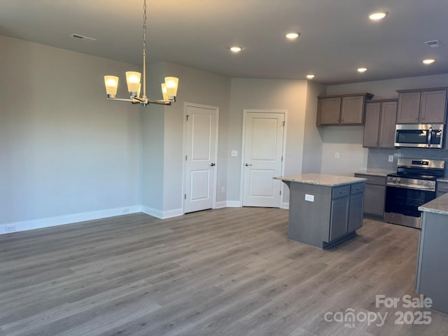 kitchen with a center island, stainless steel appliances, an inviting chandelier, decorative light fixtures, and hardwood / wood-style flooring