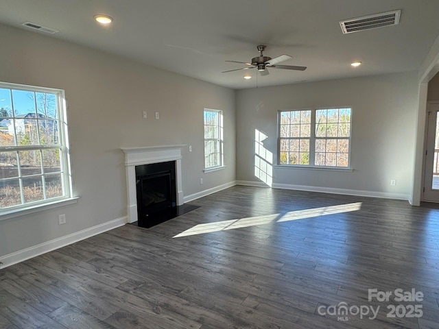 unfurnished living room featuring ceiling fan, dark hardwood / wood-style flooring, and a healthy amount of sunlight