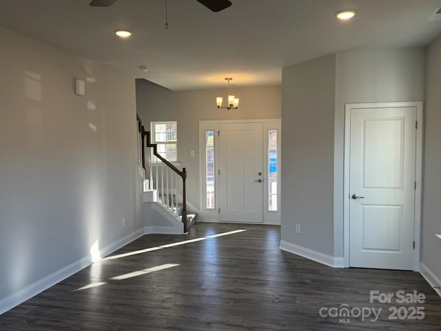 entryway featuring ceiling fan with notable chandelier and dark hardwood / wood-style flooring