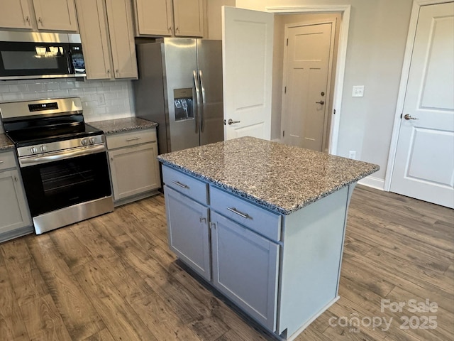 kitchen featuring dark wood-type flooring, light stone countertops, a center island, and stainless steel appliances