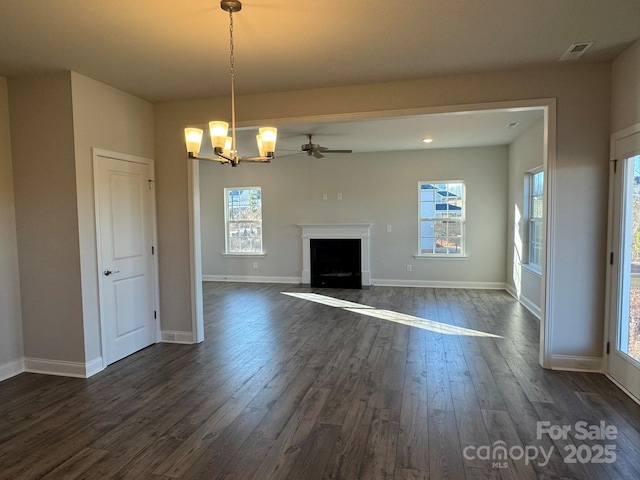 unfurnished living room featuring ceiling fan with notable chandelier and dark wood-type flooring