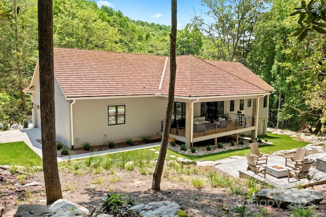 back of house with an outdoor living space with a fire pit and a patio