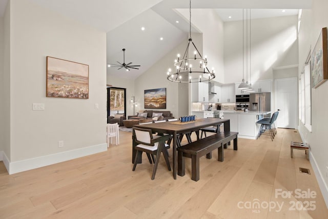 dining space with ceiling fan, light hardwood / wood-style flooring, and high vaulted ceiling