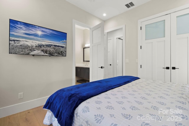 bedroom with ensuite bath, a closet, and hardwood / wood-style floors