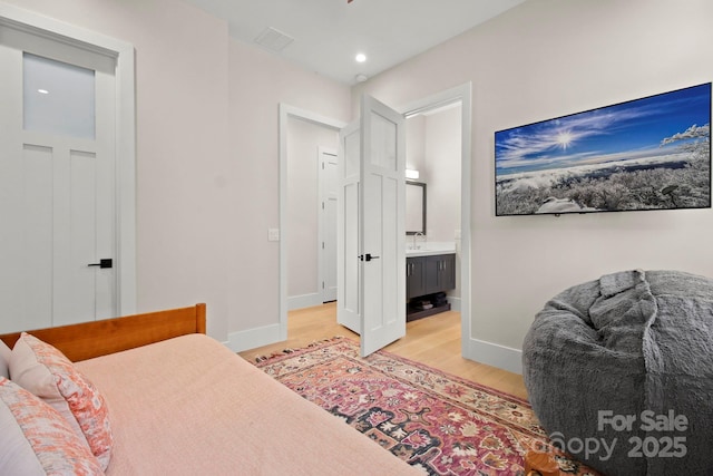 bedroom with sink, connected bathroom, and light wood-type flooring