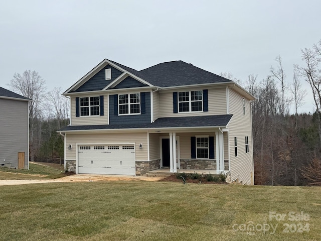 view of front of home with covered porch, a garage, and a front lawn