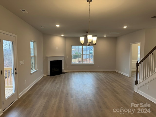 unfurnished living room featuring a chandelier and dark hardwood / wood-style floors