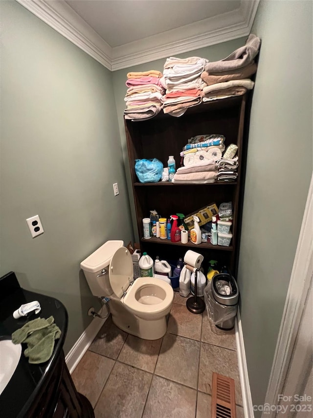 bathroom featuring toilet, ornamental molding, and tile flooring