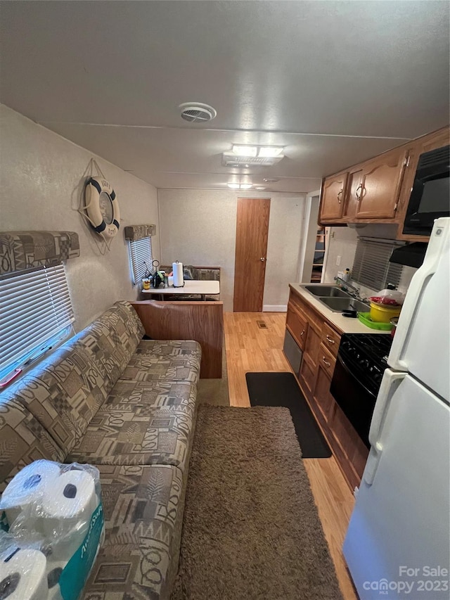 kitchen with white fridge, stove, light hardwood / wood-style flooring, and sink