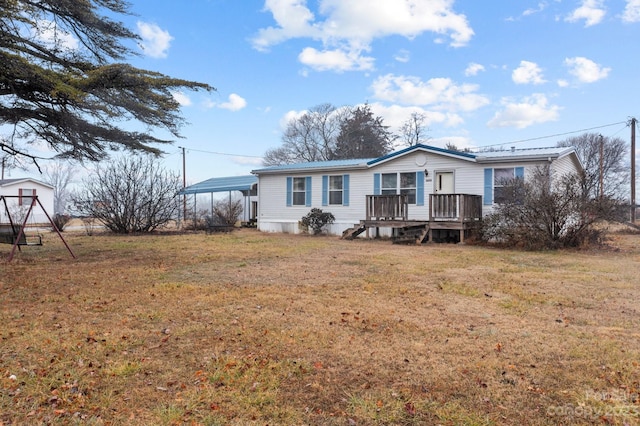 manufactured / mobile home featuring a wooden deck, a front yard, and a carport