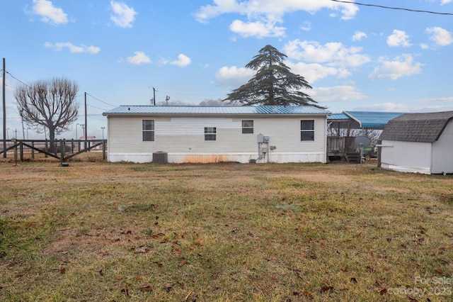 rear view of property featuring a storage unit, a yard, and central air condition unit