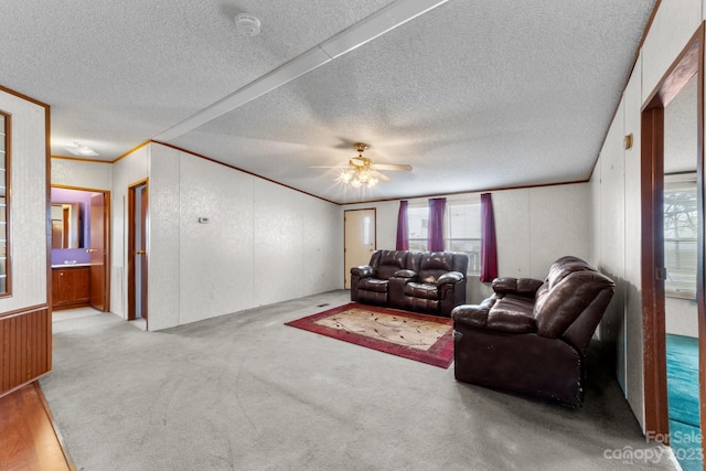 living room featuring light colored carpet, ornamental molding, ceiling fan, and a textured ceiling