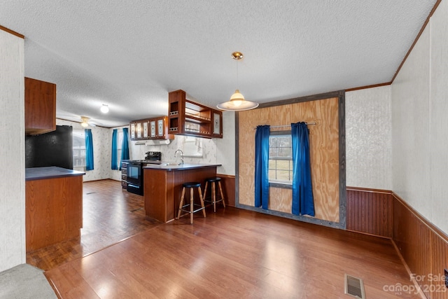 kitchen with electric stove, hanging light fixtures, a kitchen breakfast bar, and dark hardwood / wood-style floors