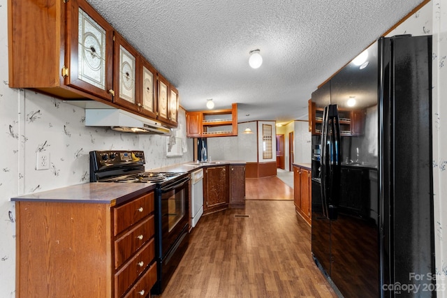 kitchen with a textured ceiling, custom range hood, wood-type flooring, and black appliances