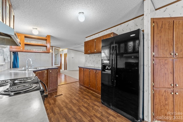 kitchen featuring range, a textured ceiling, black fridge, dark hardwood / wood-style flooring, and ornamental molding