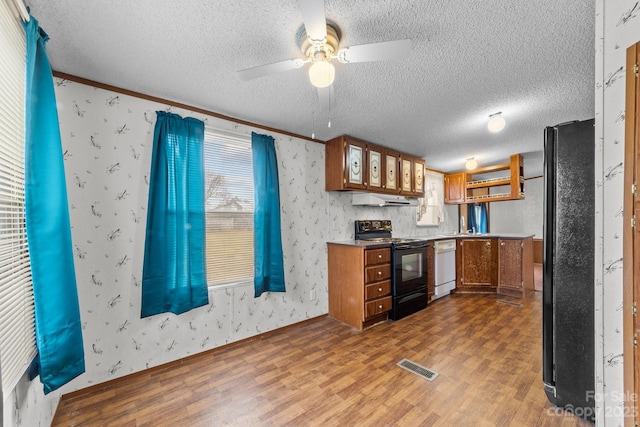 kitchen featuring ceiling fan, a textured ceiling, dark hardwood / wood-style flooring, crown molding, and black appliances