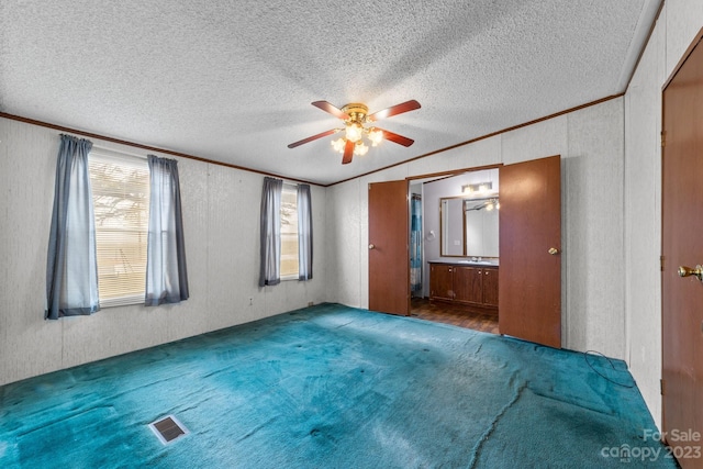 spare room featuring a textured ceiling, dark carpet, ceiling fan, and ornamental molding