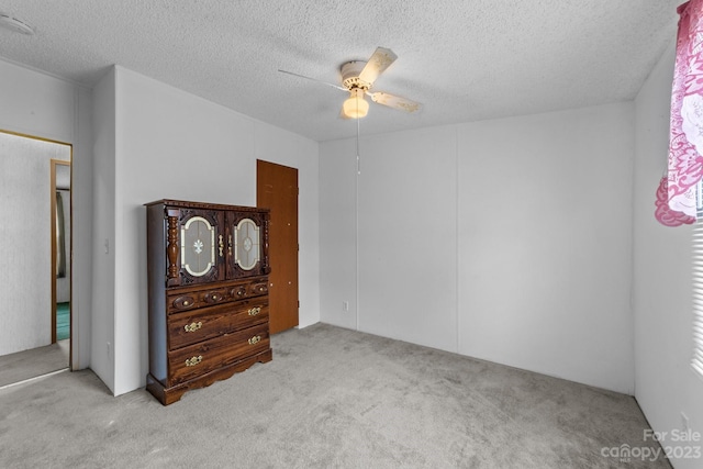 bedroom with light colored carpet, ceiling fan, and a textured ceiling