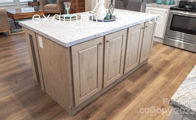 kitchen featuring electric stove, a center island with sink, light stone counters, and light hardwood / wood-style flooring