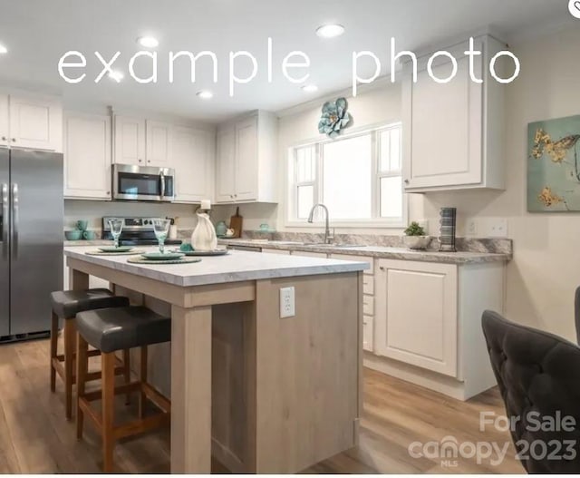 kitchen featuring a center island, stainless steel appliances, light hardwood / wood-style flooring, and white cabinetry