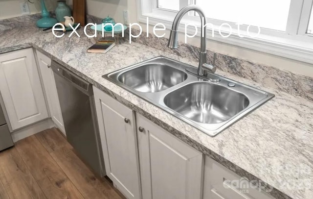 kitchen featuring light stone countertops, hardwood / wood-style floors, white cabinetry, dishwasher, and sink