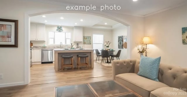 living room featuring ornamental molding, light wood-type flooring, and sink