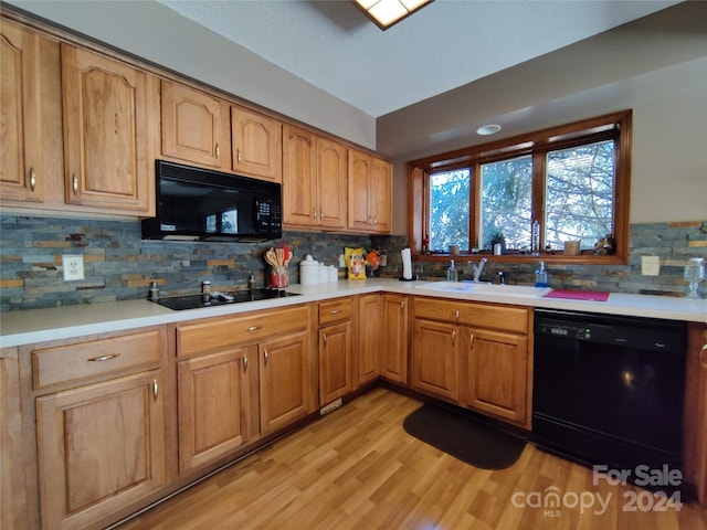 kitchen with black appliances, sink, tasteful backsplash, and light wood-type flooring