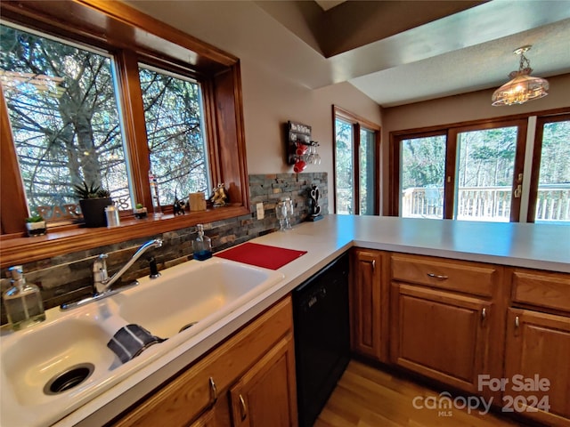 kitchen with decorative light fixtures, decorative backsplash, light wood-type flooring, sink, and dishwasher