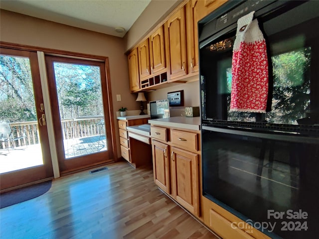 kitchen featuring black double oven, a healthy amount of sunlight, and light wood-type flooring