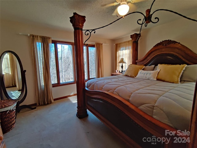 bedroom with ceiling fan, carpet floors, and a textured ceiling