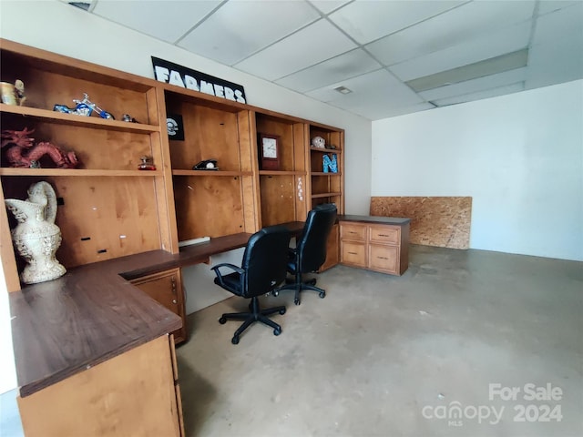 home office with a drop ceiling and concrete flooring