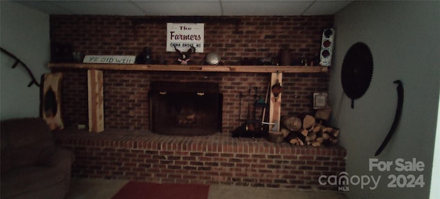 living room featuring a drop ceiling and a brick fireplace