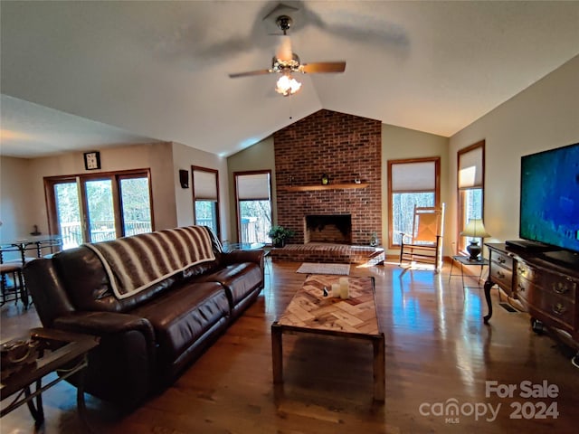 living room featuring hardwood / wood-style floors, vaulted ceiling, a fireplace, brick wall, and ceiling fan