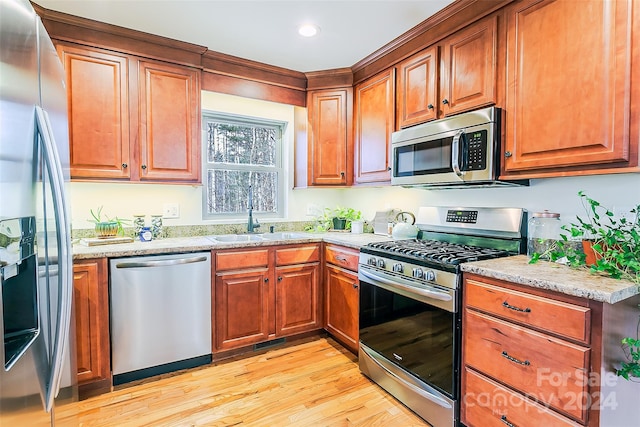 kitchen featuring sink, light wood-type flooring, stainless steel appliances, and light stone countertops