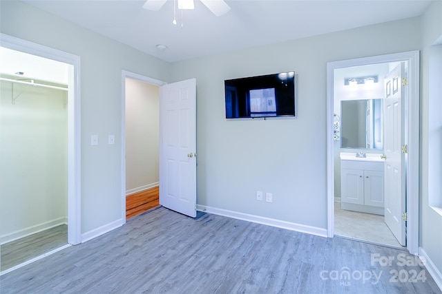 unfurnished bedroom featuring a closet, ceiling fan, connected bathroom, light wood-type flooring, and a walk in closet